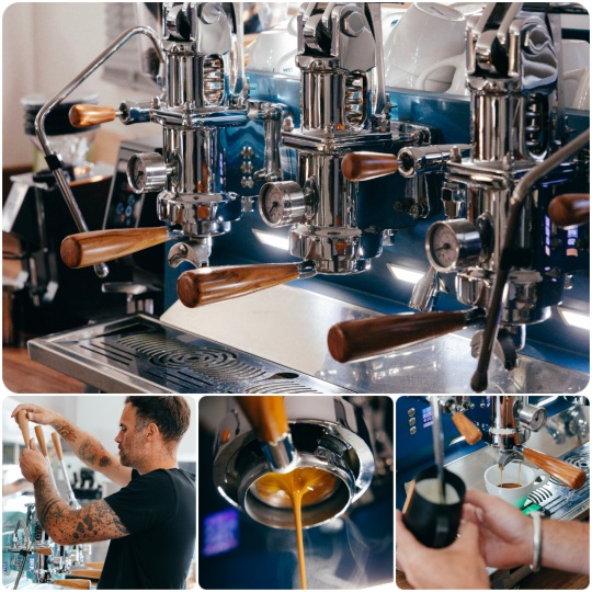 Hearthside's espresso bar: a polished blue La Marzocco group head, a barista dialling in a grind, a naked portafilter pulling a shot, and milk being steamed.